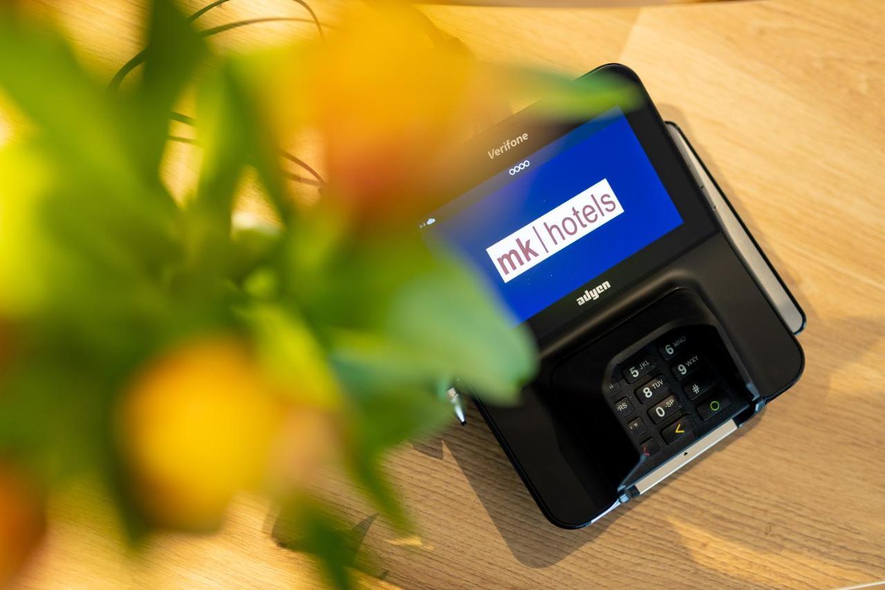 Mk Hotel Tirana Rinas Екстериор снимка A mobile phone with the MK1Hotels logo on the screen